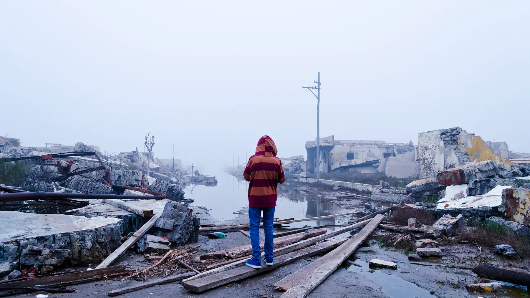 Young Argentinian boy stands in remains of town after a flood